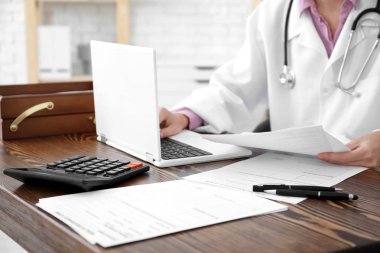 Belgeler ve dizüstü ofiste çalışan kadın doktor. Sağlık sigortası kavramı