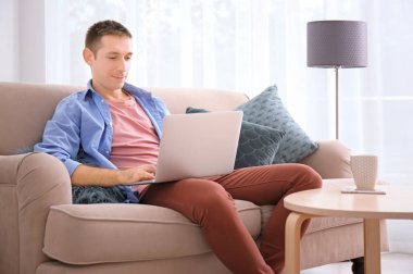 Genç adam rahat kıyafetler dizüstü evde kullanma