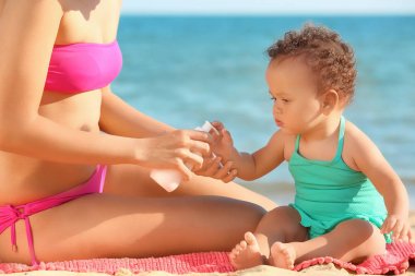 Genç Afrikalı-Amerikalı anne ve kızı ile güneş kremi Beach Resort