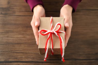 Parsel hediye kutusu ahşap arka plan üzerinde tutan kadın