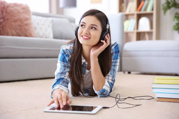 Donna che ascolta audiolibro attraverso le cuffie a casa — Foto Stock