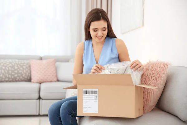 Junge Frau öffnet Paket im Haus — Stockfoto