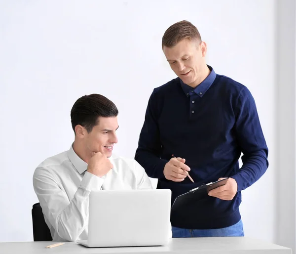 Unga män med laptop på ljus bakgrund — Stockfoto