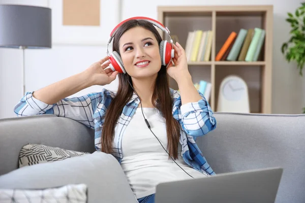 Donna che ascolta audiolibro attraverso le cuffie a casa — Foto Stock