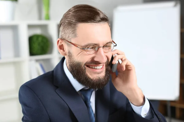 Hombre de negocios guapo hablando por teléfono celular en el interior — Foto de Stock