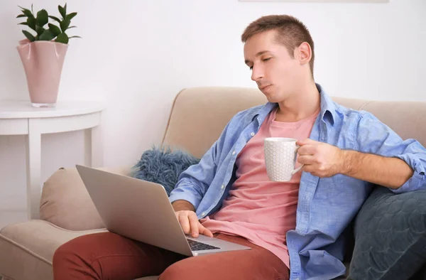 Jovem em roupas casuais usando laptop em casa — Fotografia de Stock