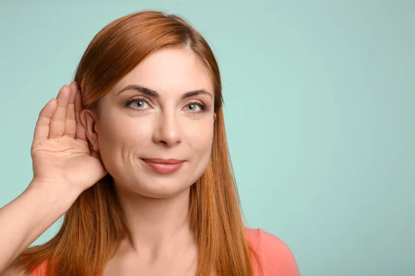 Young woman with hearing problem on color background — Stock Photo, Image