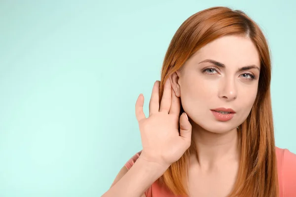 Молодая женщина с проблемами со слухом на цветном фоне — стоковое фото