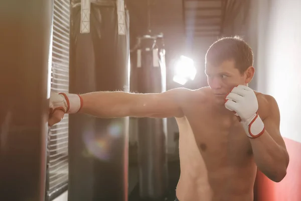 Entrenamiento de boxeador masculino con saco de boxeo en gimnasio —  Fotos de Stock