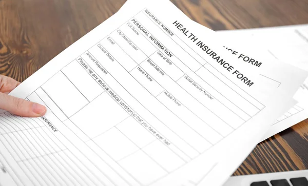 Woman with health insurance forms at table, closeup