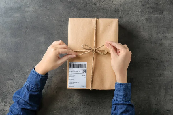 Жінка з посилкою подарункова коробка на сірому фоні — стокове фото