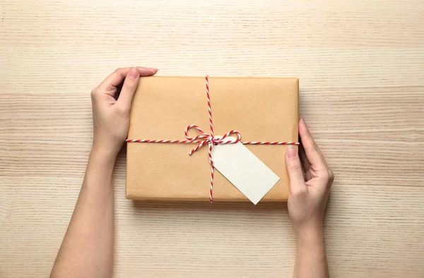 Frau mit Paket-Geschenkbox auf Holz-Hintergrund — Stockfoto