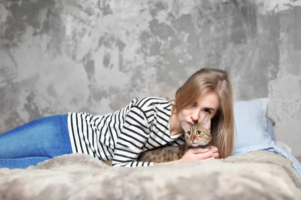 Schöne junge Frau mit süßer Katze auf dem Bett zu Hause — Stockfoto