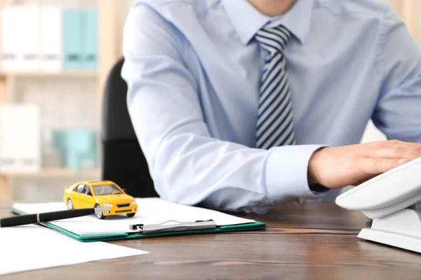 Man met telefoon aan tafel. Auto verzekering concept — Stockfoto