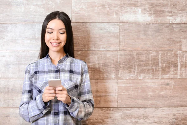 Belle jeune femme avec téléphone portable près du mur en bois — Photo