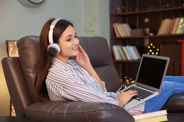 Donna che ascolta audiolibro attraverso le cuffie a casa — Foto Stock