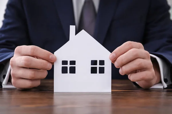 Real estate agent with paper cut of house at table. Insurance concept — Stock Photo, Image