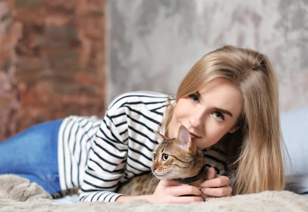 Schöne junge Frau mit süßer Katze auf dem Bett zu Hause — Stockfoto