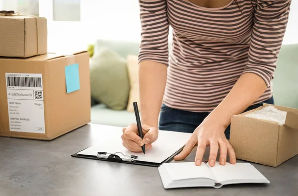 Jeune femme préparant des colis pour l'expédition aux clients à table au bureau à domicile. Démarrage d'entreprise — Photo