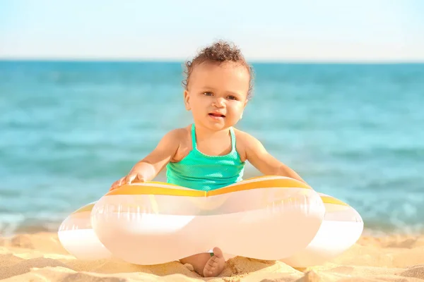 Kleines Mädchen mit aufblasbarem Ring am Strand des Resorts — Stockfoto
