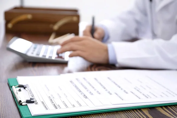 Schránka s formuláři zdravotního pojištění a lékař u stolu — Stock fotografie