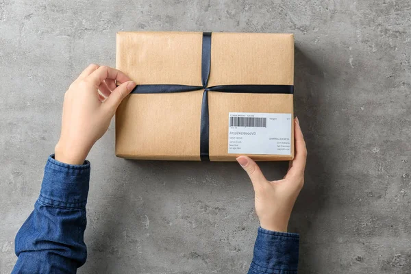 Mujer con caja de paquete sobre fondo gris — Foto de Stock