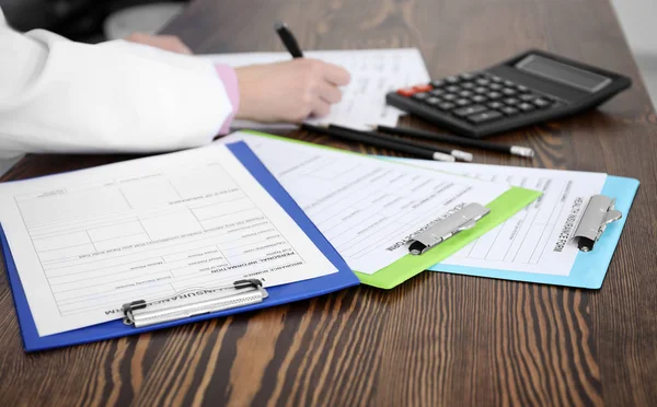 Portapapeles con formularios de seguro de salud y médico en la mesa — Foto de Stock