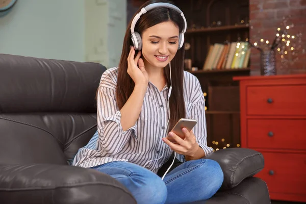 Donna che ascolta audiolibro attraverso le cuffie a casa — Foto Stock