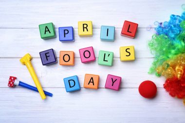 Parti boynuzları, küpler ve gökkuşağı peruk ahşap arka plan üzerinde. Nisan bir günü kutlama