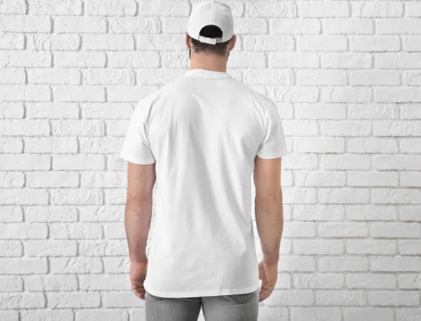 Bonito jovem em elegante t-shirt branca perto da parede de tijolo. Mockup para design — Fotografia de Stock