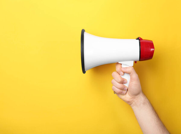 Человек держит мегафон на цветном фоне
