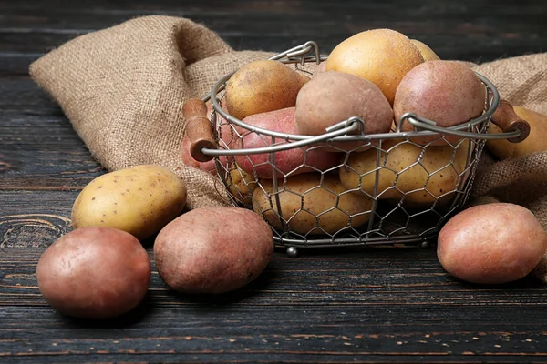 Cesta com batatas cruas frescas na mesa de madeira — Fotografia de Stock