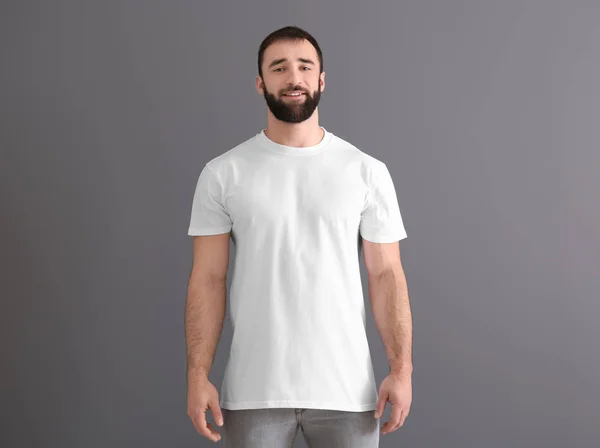 灰色の背景にスタイリッシュな白い t シャツでハンサムな若い男。デザインのモックアップ — ストック写真