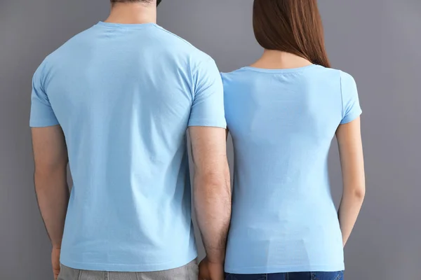 Giovane uomo e donna in eleganti t-shirt su sfondo grigio. Mockup per il design — Foto Stock