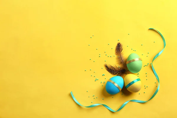 Decorato uova di Pasqua e piume su sfondo di colore — Foto Stock