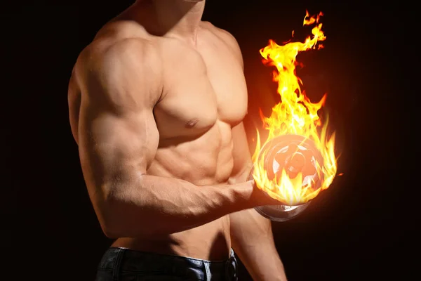 Muskulöser junger Bodybuilder, der hart mit brennender Hantel auf schwarzem Hintergrund trainiert — Stockfoto