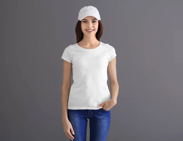 Vacker ung kvinna i snygg vit t-shirt på grå bakgrund. Mockup för design — Stockfoto