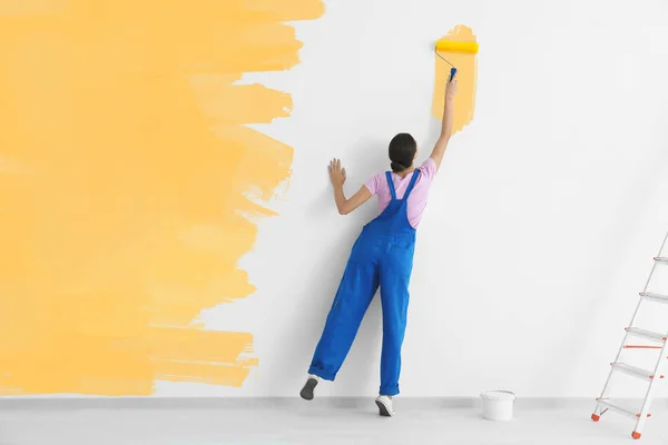 Decorador pintura parede branca na cor amarela com rolo — Fotografia de Stock