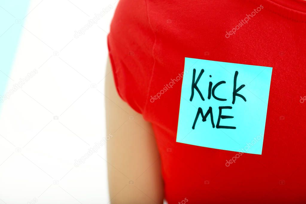 Sticky note with phrase Kick me on womans back, closeup. April fools day prank