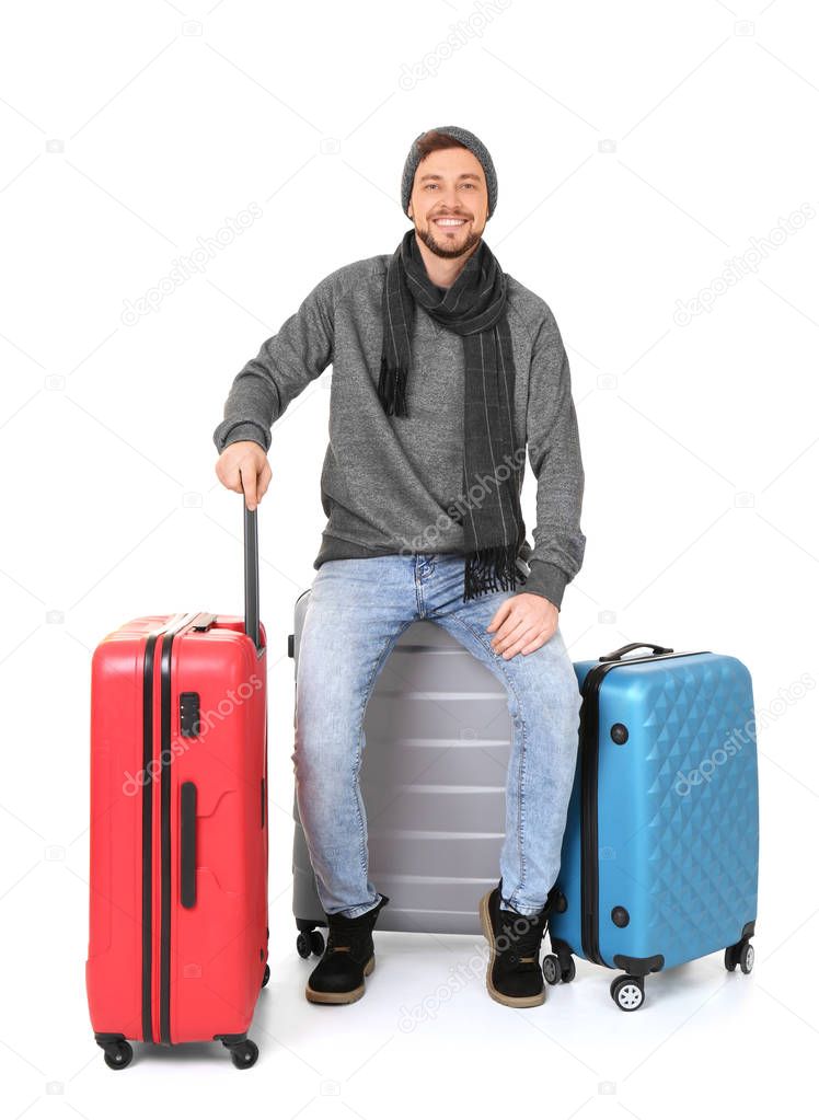 Young man in warm clothing with luggage on white background. Ready for winter vacation