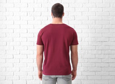 Beyaz tuğla duvar yakınındaki şık tişört yakışıklı genç adam. Mockup tasarım için