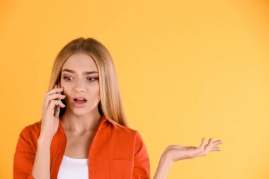 Genç kadın renk arka plan karşı cep telefonuyla söz