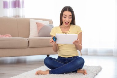 Genç kadın alışveriş online kredi kartı ve evde tablet ile