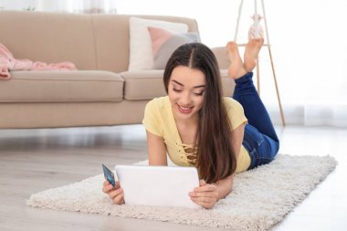 Genç kadın alışveriş online kredi kartı ve evde tablet ile