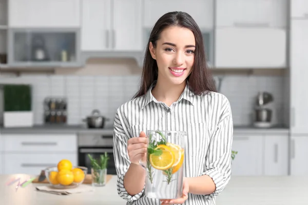 Giovane donna con brocca di vetro di limonata al chiuso — Foto Stock