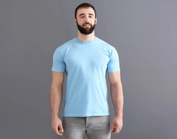 Bonito jovem em elegante t-shirt em fundo cinza. Mockup para design — Fotografia de Stock