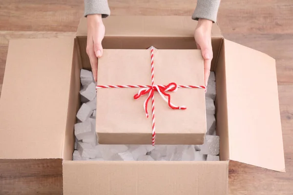 Mujer tomando caja de regalo fuera de paquete en el interior — Foto de Stock