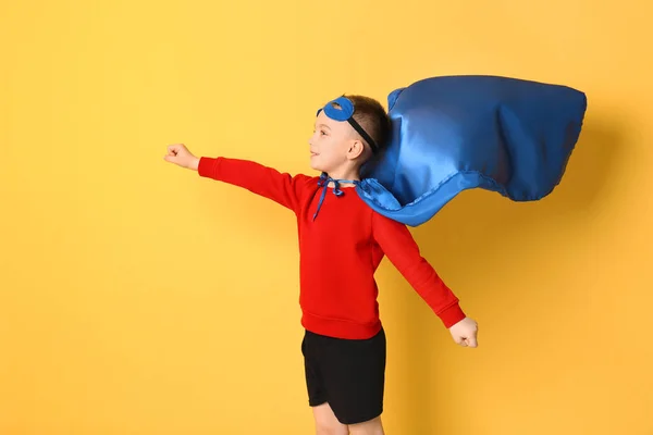Cute boy in superhero costume on color background — Stock Photo, Image