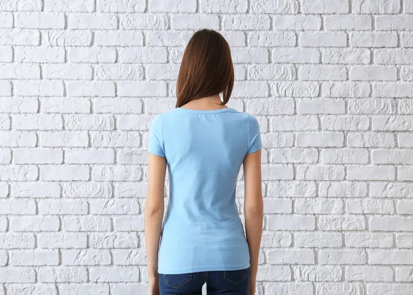Hermosa mujer joven en elegante camiseta cerca de la pared de ladrillo blanco. Burla para el diseño —  Fotos de Stock