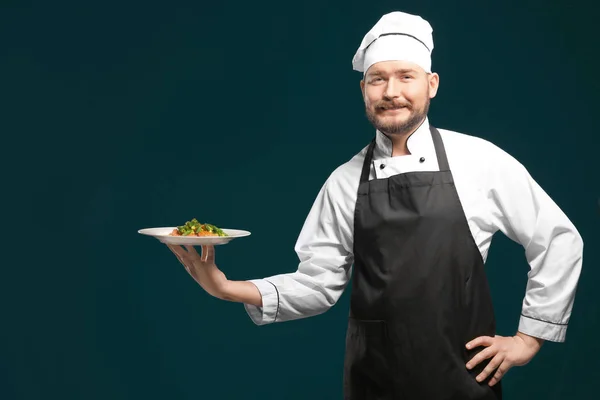 Красивий чоловічий шеф-кухар тримає тарілку з тарілкою на кольоровому фоні — стокове фото